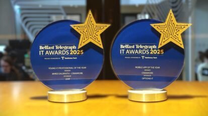Two blue Belfast Telegraph IT Award trophies on a desk. One for Mobile App of the Year and the other for Young IT Professional of the Year.